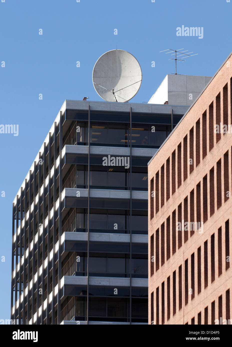 Communications satellite dish on top of building Stock Photo