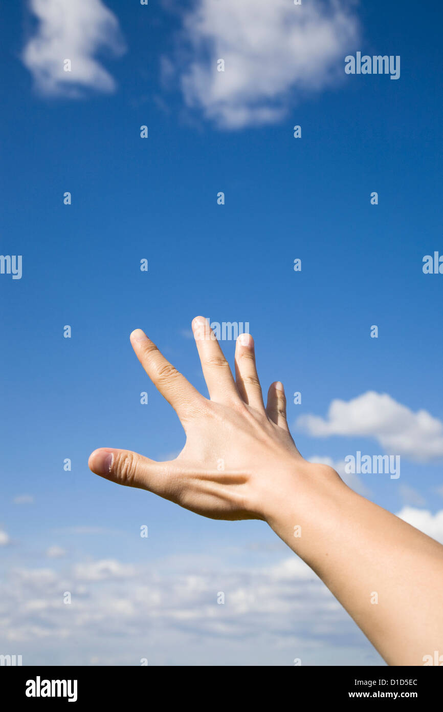 Man's hand reaching up to the blue sky. Stock Photo