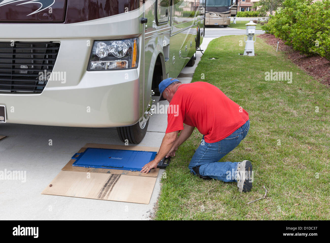 Man places portable scale in position to weigh motor coach at RV resort in Brunswick, Georgia Stock Photo