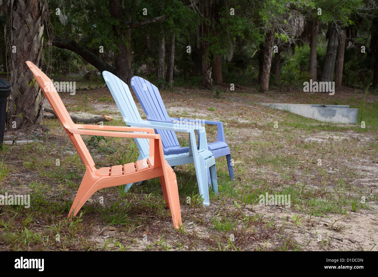 Pastel plastic lawn chairs in poorly manicured lawn Stock Photo