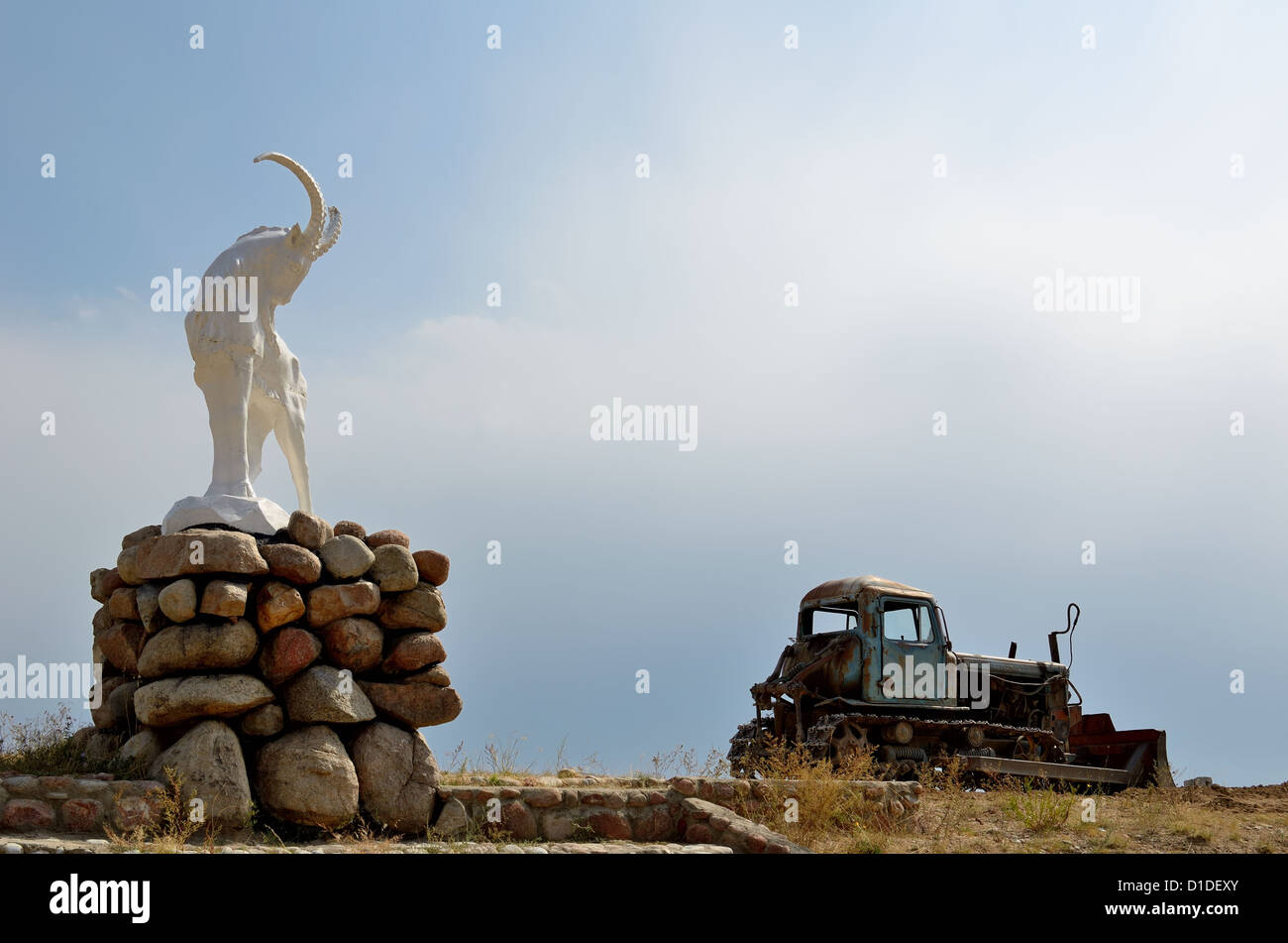 Sculpture of a stone goat and old tractor in Issyk-Kul region of Kyrgyzstan Stock Photo