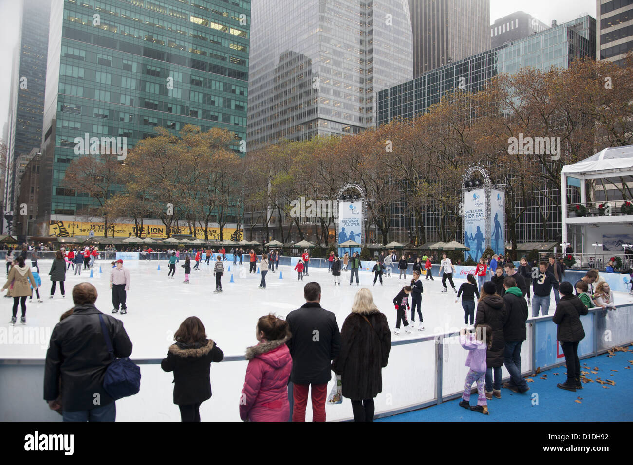 The ice skating rink is always busy in Bryant Park during the holiday season behind the NY Public Library in NYC. Stock Photo