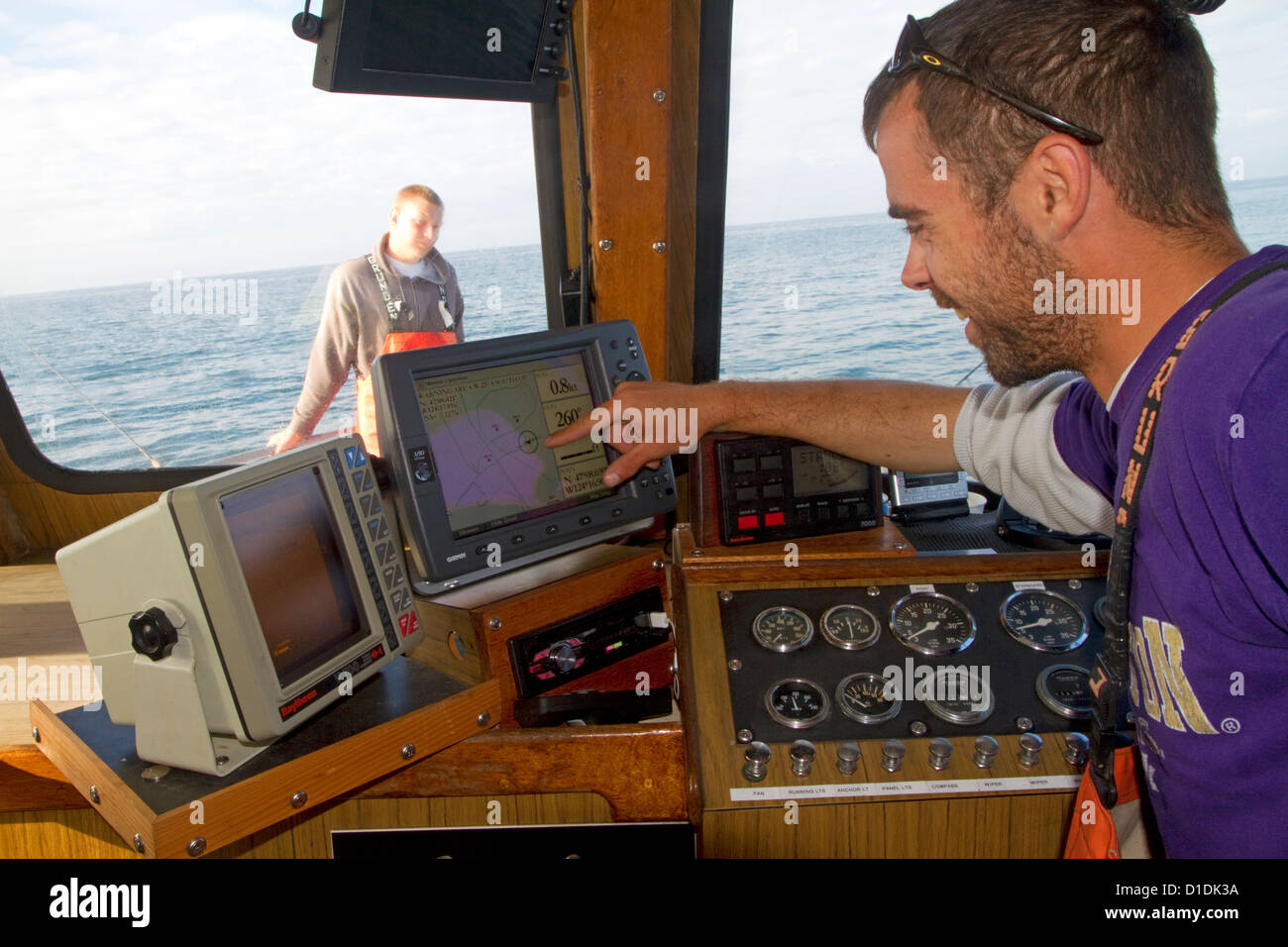 Fishing boat skipper checks the GPS receiver on a fishing boat in the Pacific Ocean off the coast of Westport, Washington, USA. Stock Photo