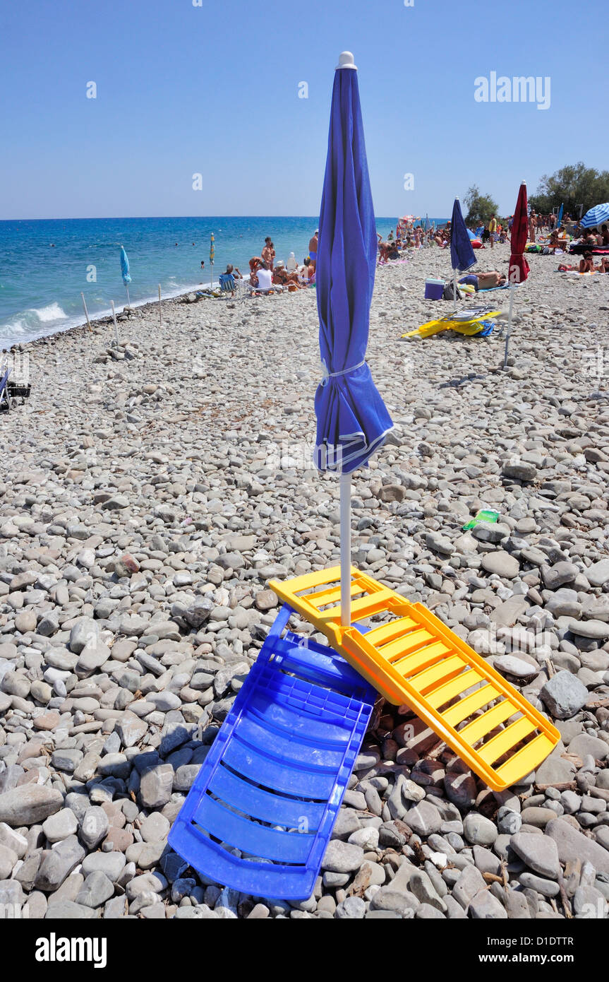Beach chairs and umbrella on pebble beach Stock Photo