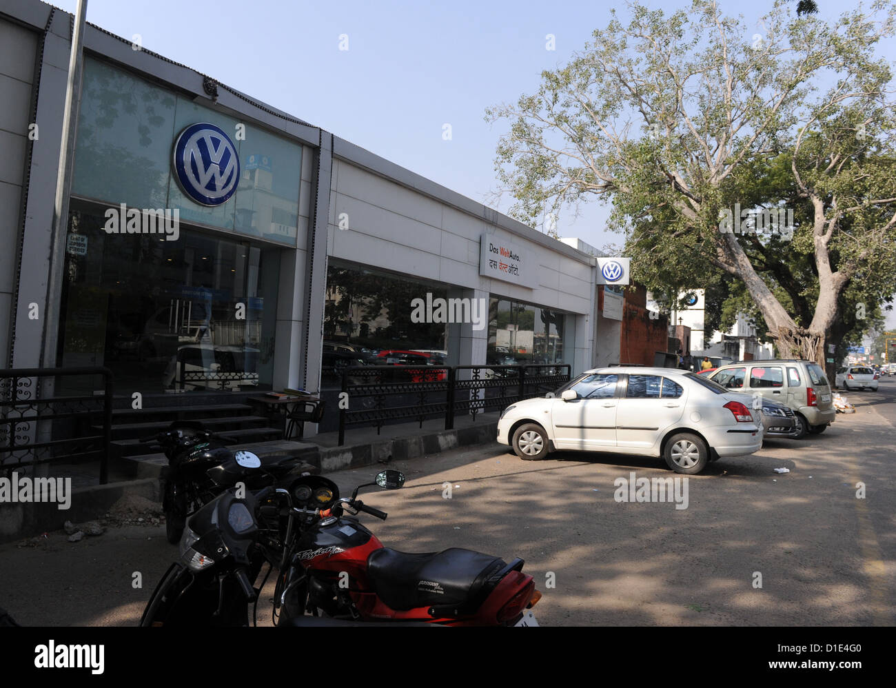 Cars and a motorbike are parked in front of a VW car dealership in Jaipur, India, 19 November 2012. On the store front of the dealership, VW advertises with the slogan 'Das Weltauto' (The world car) in German and Hindi. Photo: Jens Kalaene Stock Photo