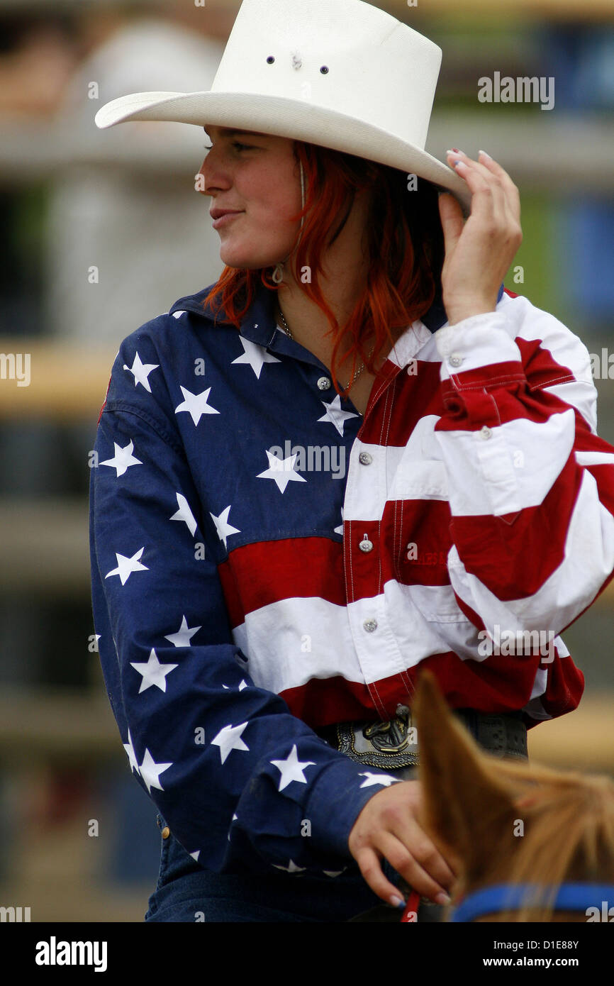 cowgirl riding in a American flag shirt with hat Stock Photo
