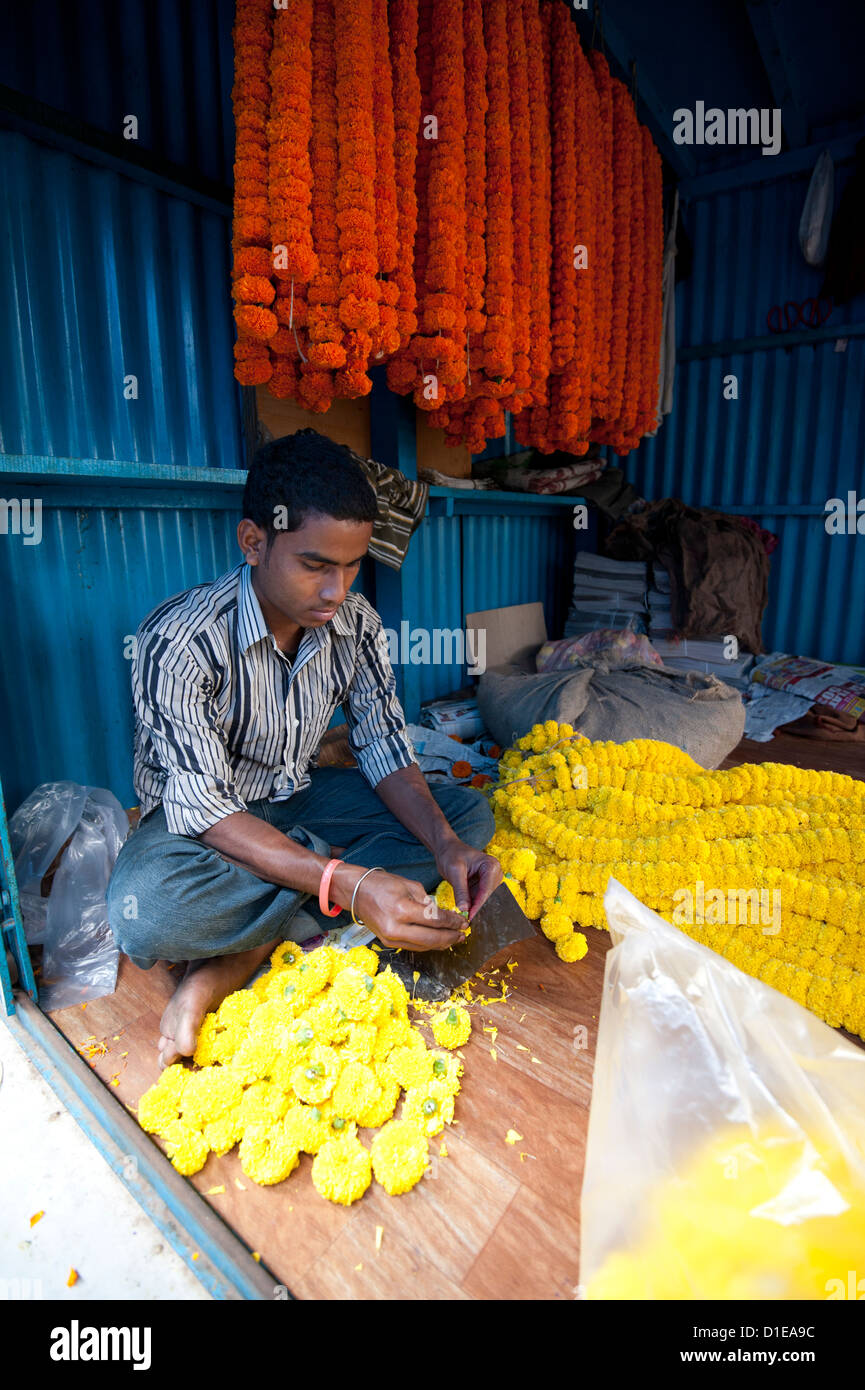 Mala maker (garland maker) at work with marigolds in morning flower market, Howrah, Kolkata