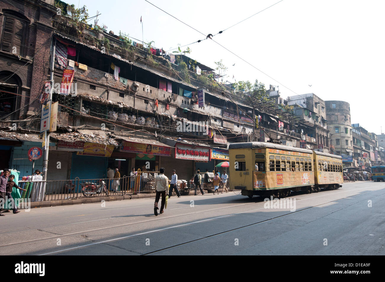 Yellow Kolkata tram passing Kolkata slums in the early morning, Kolkata, West Bengal, India, Asia Stock Photo