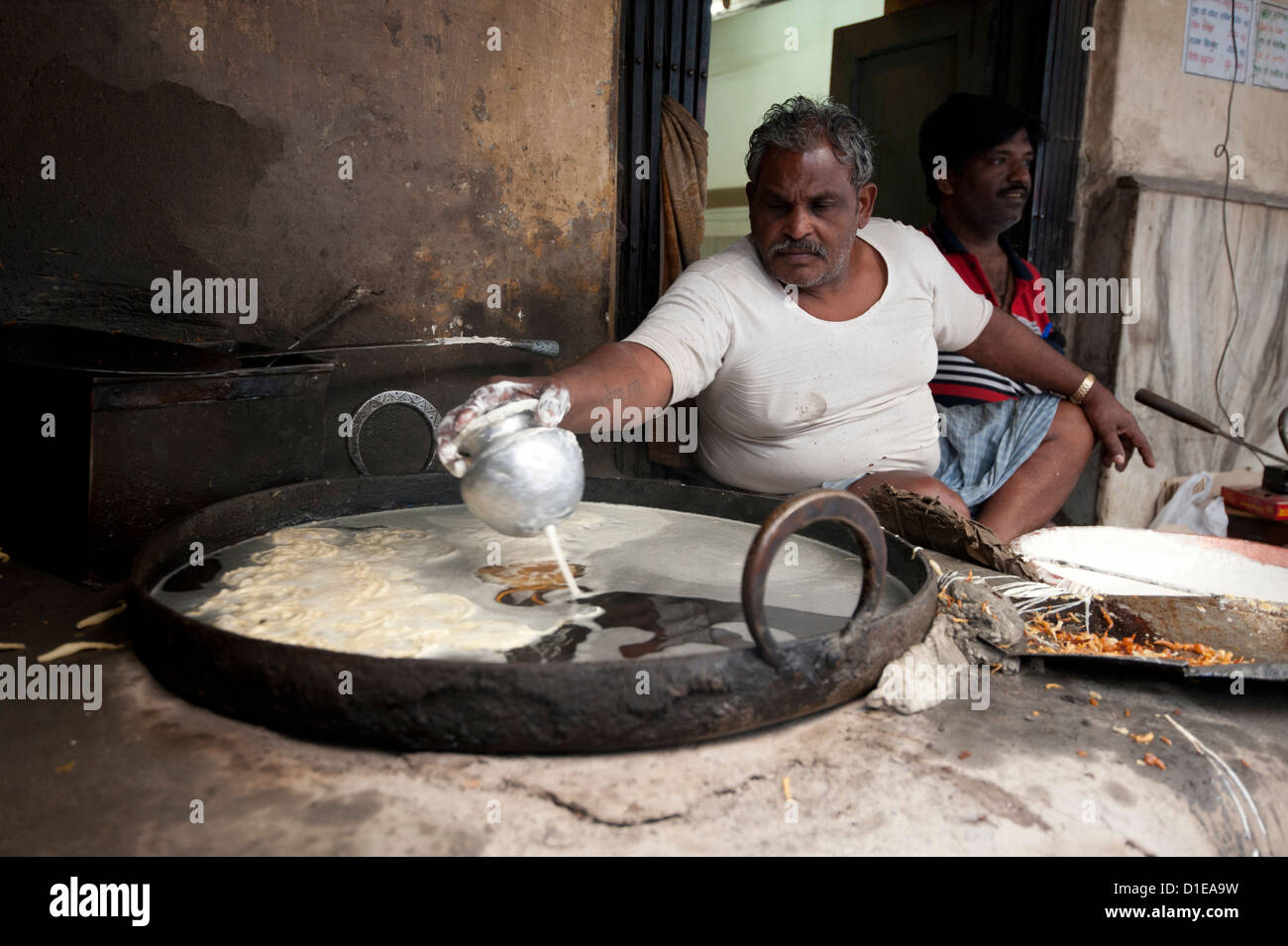 Jalebi wallah dripping sweet rice flour paste into hot fat to make