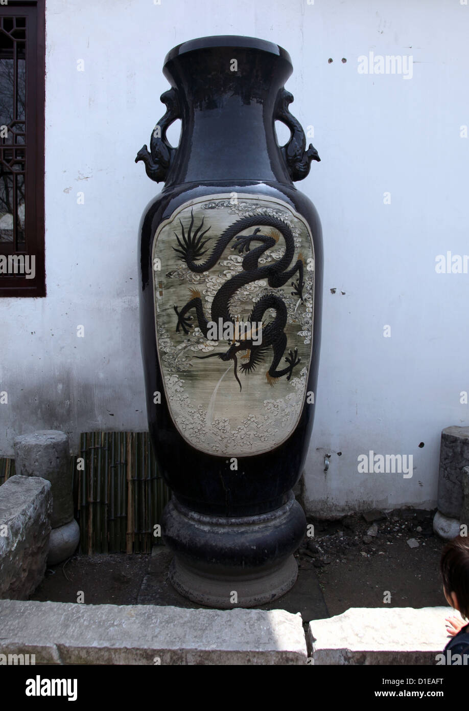 it's a photo of a ancient old ming Chinese vase that is in a corner of a Garden in a temple in china. There is a dragon painted Stock Photo