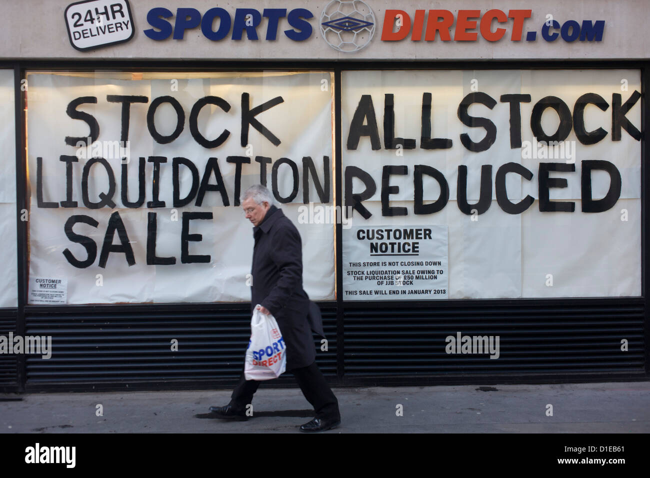 An all reduced sale of sports clothing supplier JJB.com stock, being sold by new buyer, Sports Direct shop in central London. A male shopper walks past the store window with a Sports Direct bag, passing the large lettering painted onto the glass, declaring the stock sale.  JJB Sports has collapsed into administration, with arch-rival Sports Direct acquiring 20 stores. KPMG partners Brian Green, David Costley-Wood and Richard Fleming were appointed administrators before Sports Direct bought the JJB assets for £23.77m. Stock Photo