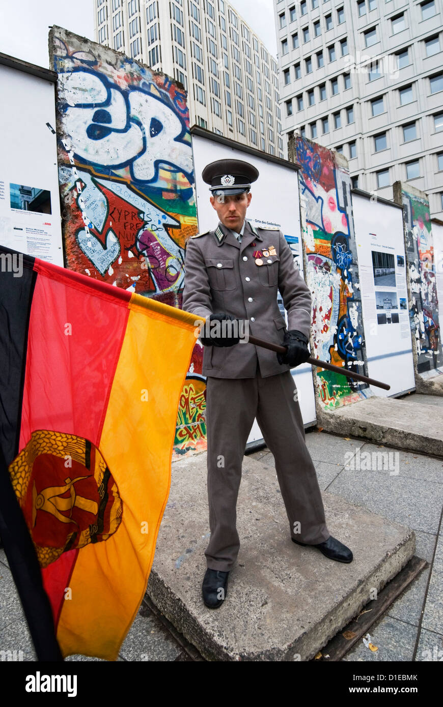 East German guard with former GDR flag in front of remains of the Berlin Wall, Potsdamer Platz, Berlin, Germany, Europe Stock Photo