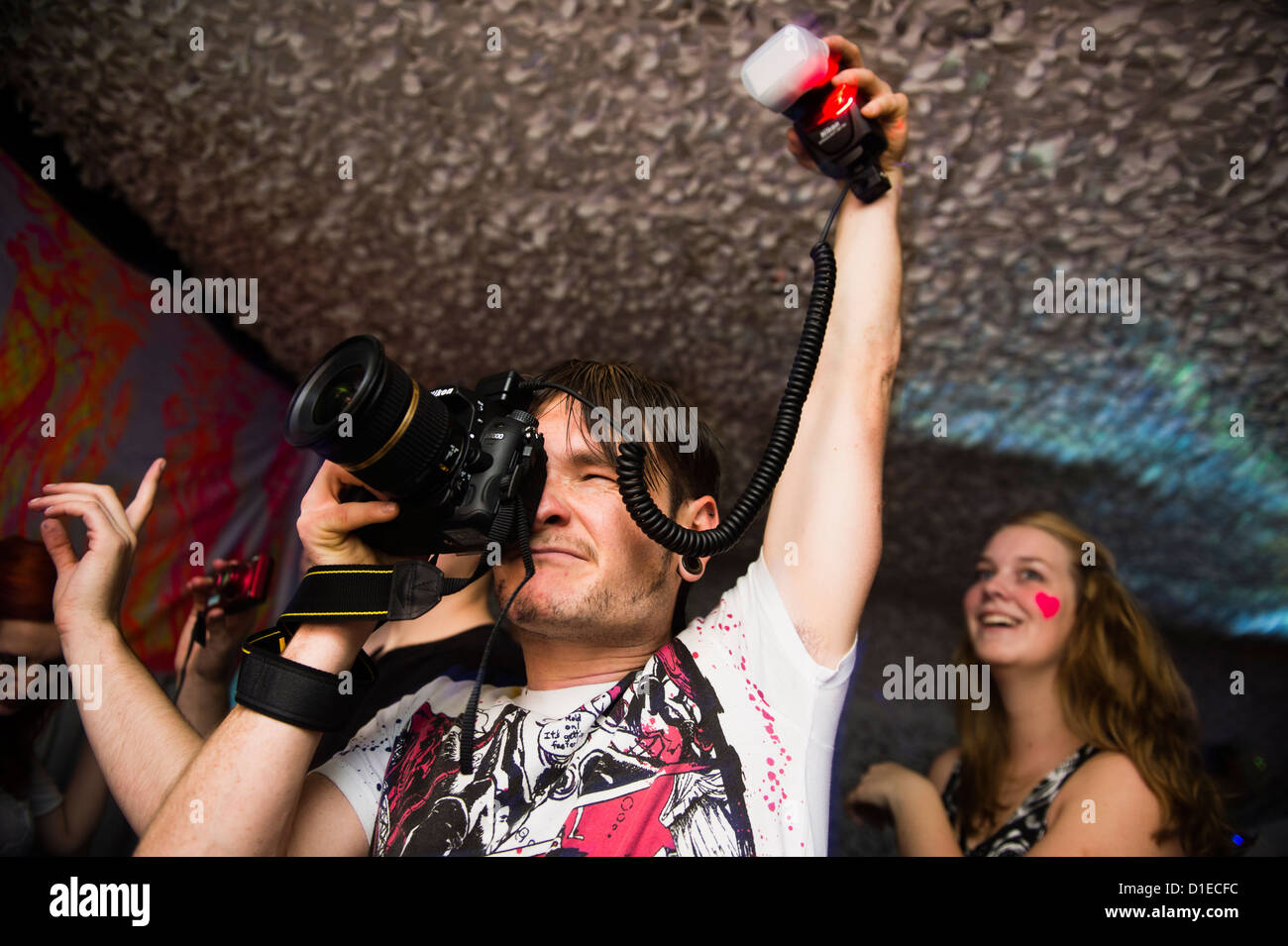 A young male photographer holding a flash gun photographing people