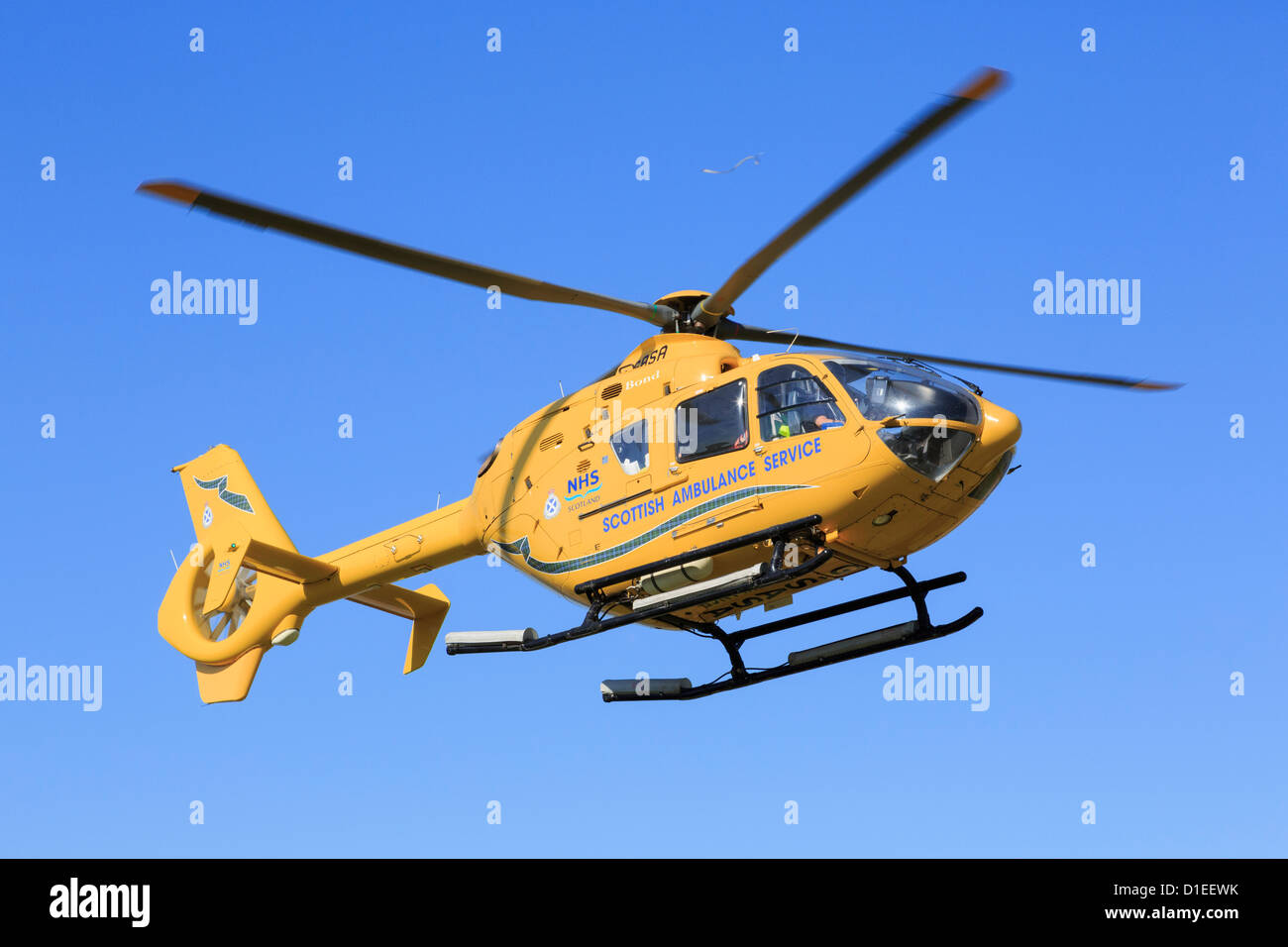 Yellow Scottish Air Ambulance Service Helicopter flying overhead with a casualty from a rescue mission. Sutherland Scotland UK Stock Photo