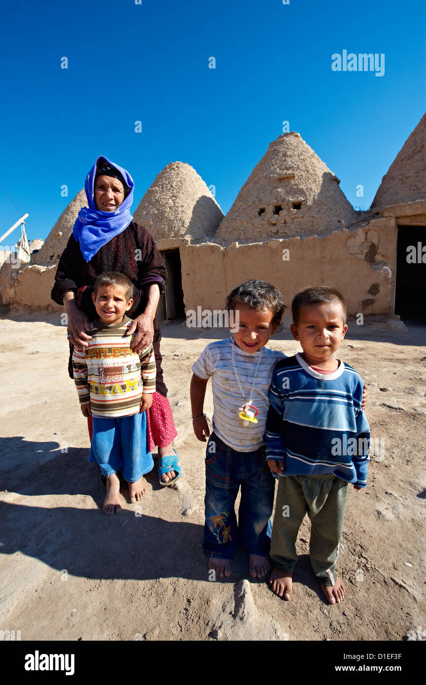 Family in front of the beehive adobe houses of Harran, south west Anatolia, Turkey. Stock Photo
