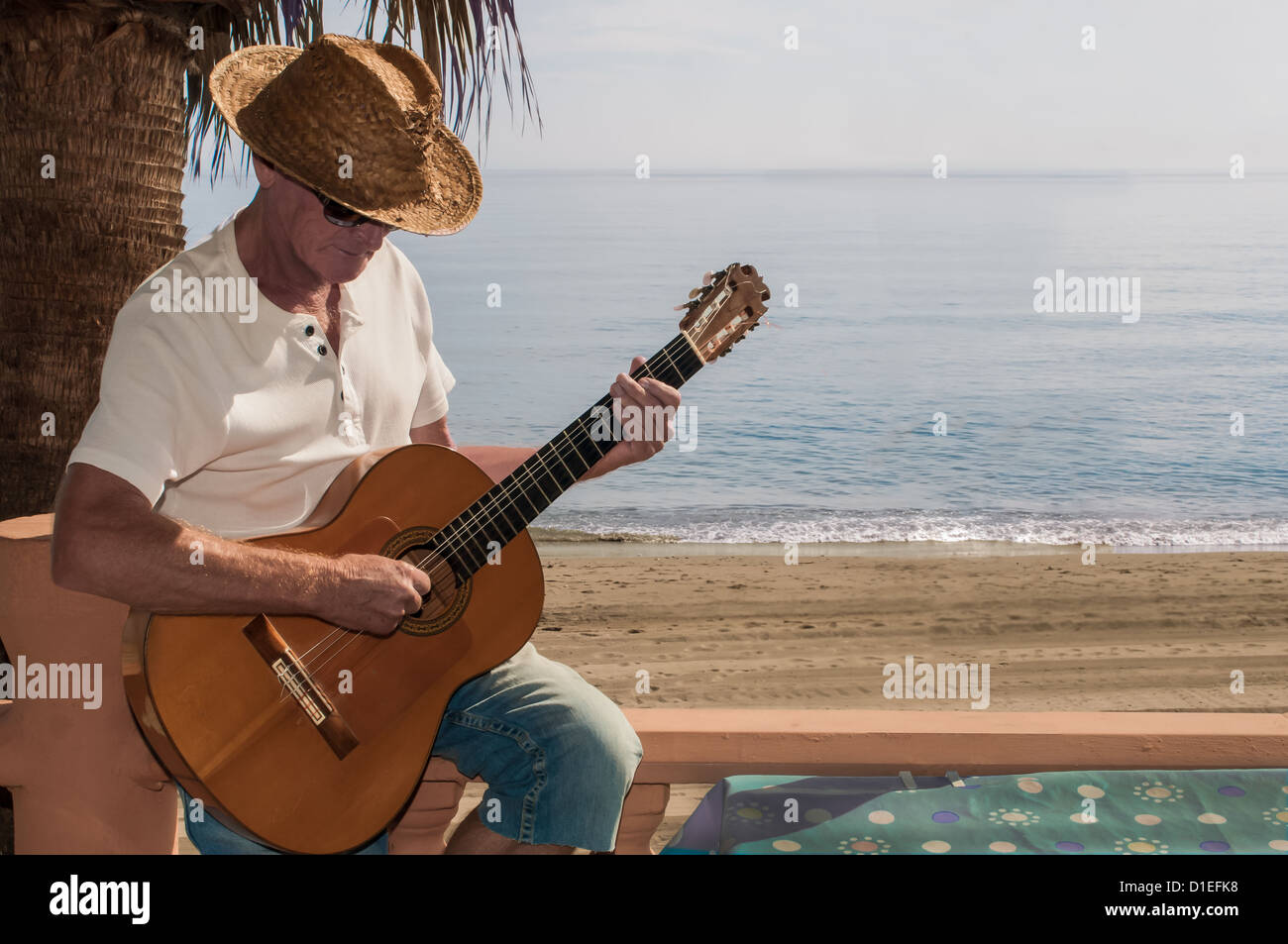 Mature man playing romantic guitar at a Spanish beach restaurant Stock Photo