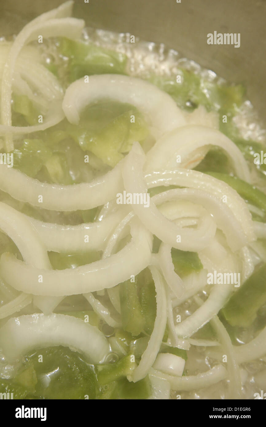 chopped green peppers and white onions cooking in vegetable oil Stock Photo