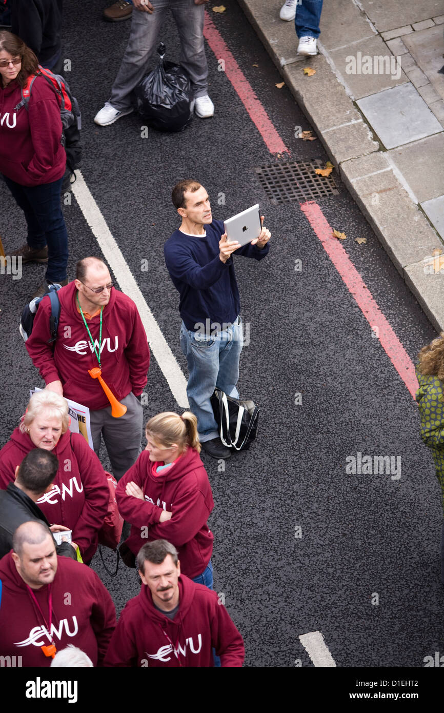 Marcher / protestor / photographer taking a photo / photograph / snap with an iPad / i Pad during a union march in London, UK. Stock Photo