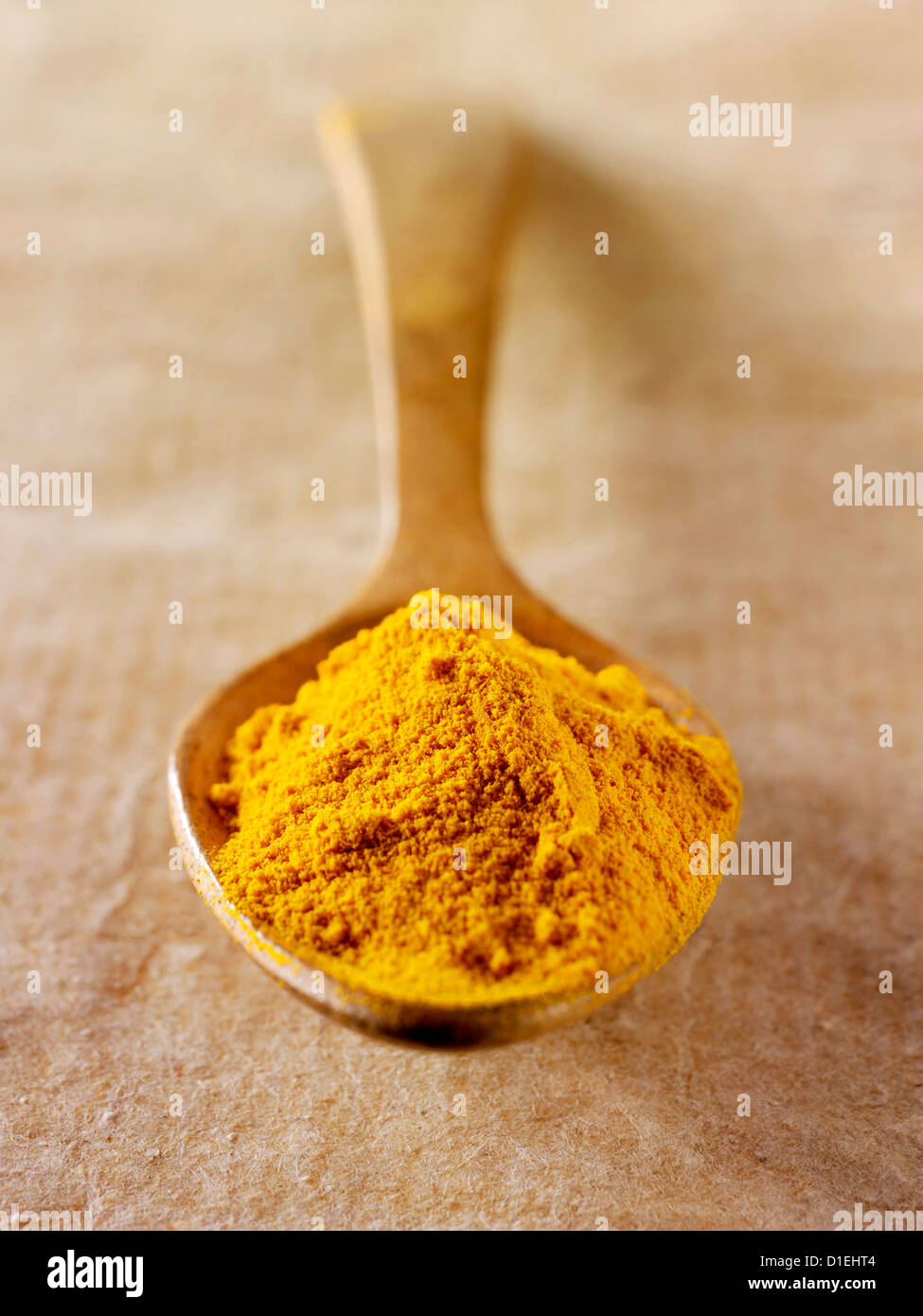 Turmeric spice powderin a wooden spoon against a natural background