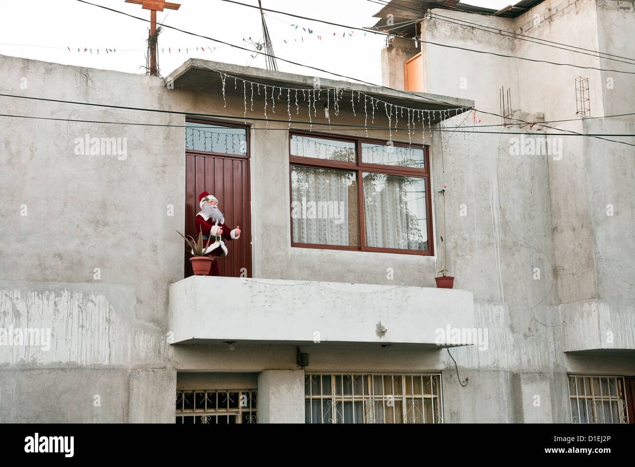 jolly Santa Claus figure & string of icicle lights decorate balcony of concrete house for the Christmas season Oaxaca de Juarez Stock Photo