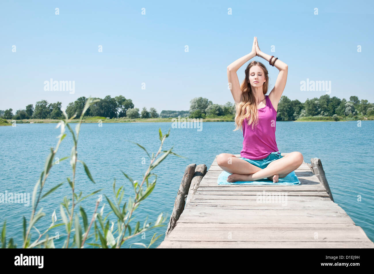 Blond young woman practicing yoga at a lake Stock Photo - Alamy