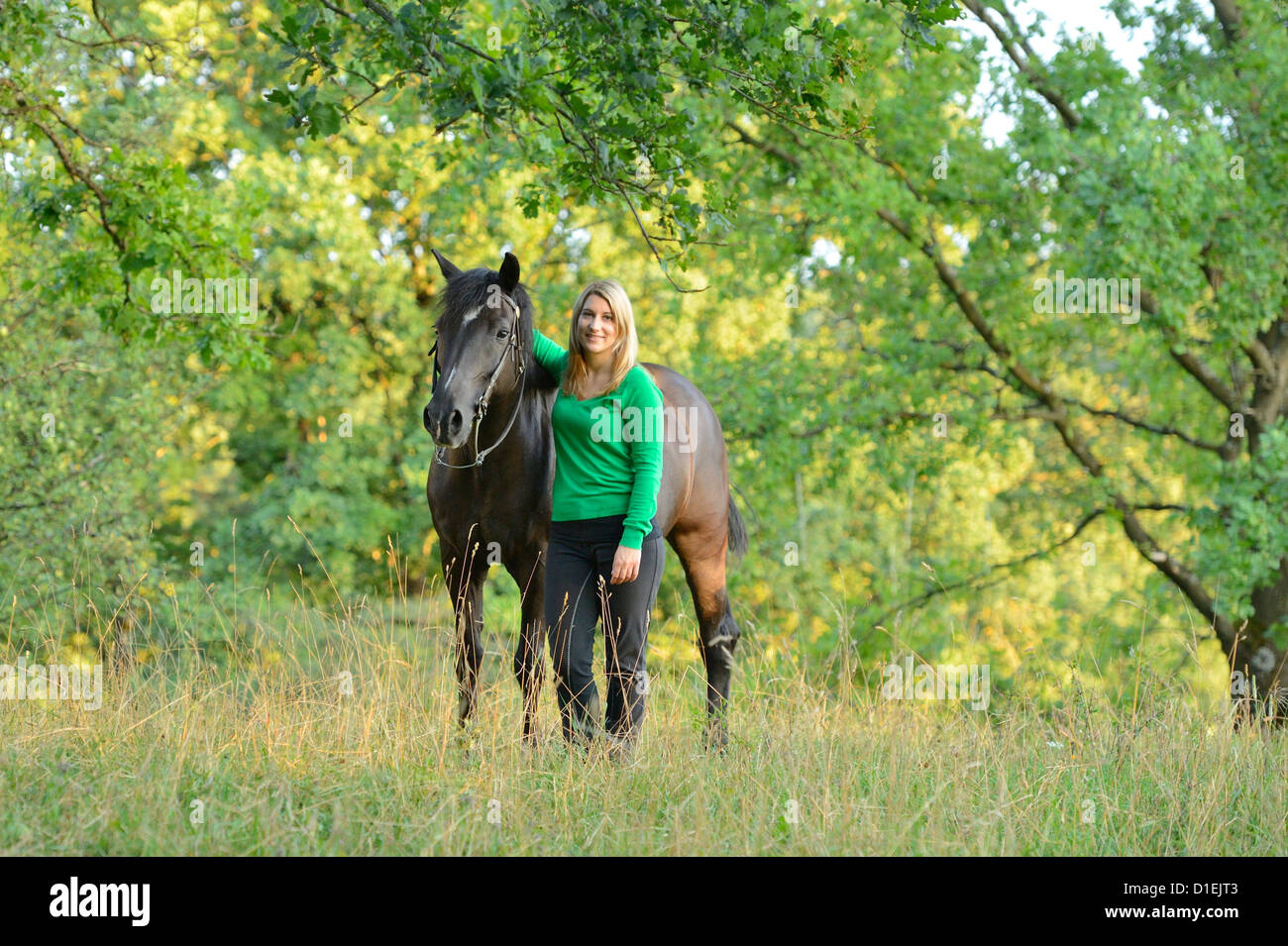 Smiling teenage girl with horse on meadow Stock Photo - Alamy