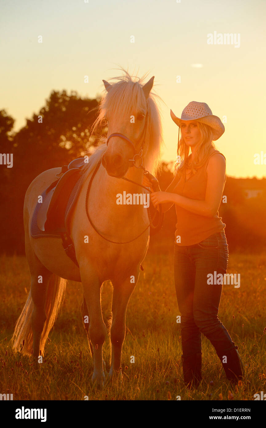 Young woman with horse on meadow in backlight Stock Photo