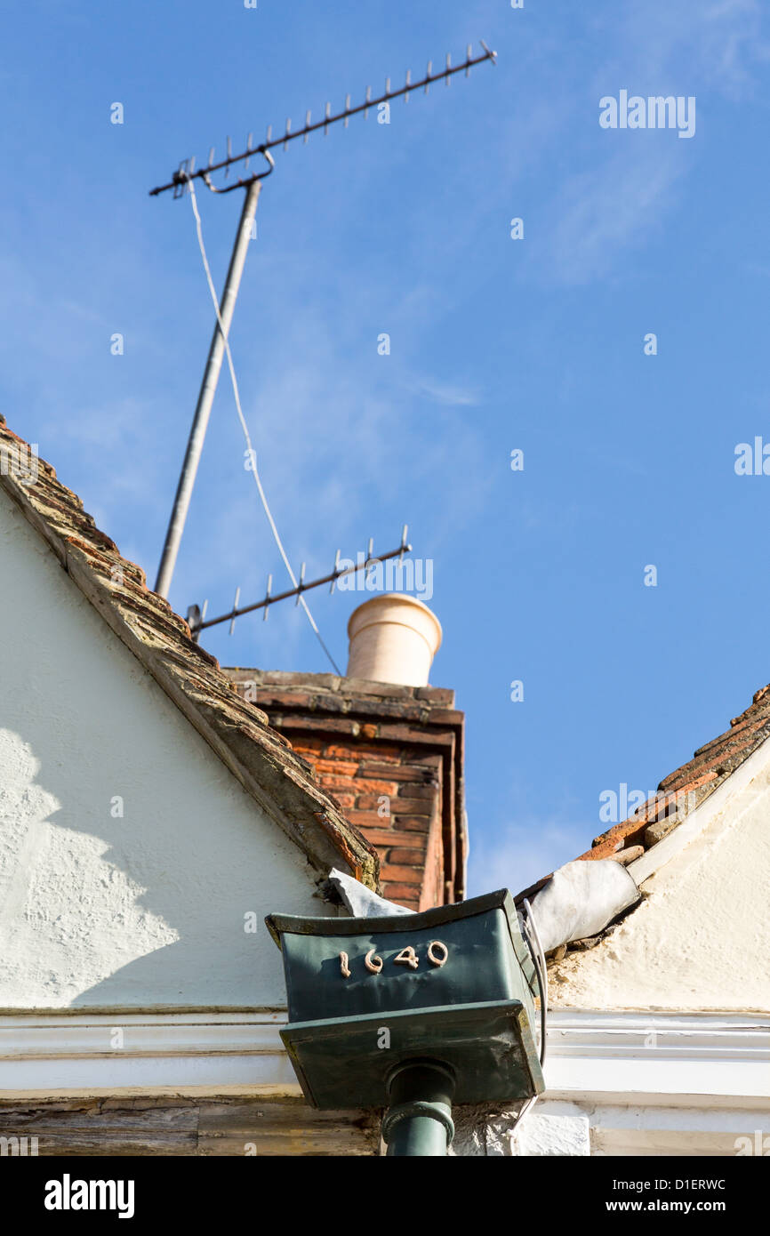 Contrast of old and new with TV aerial and old lead gutter drainpipe on roof of house Stock Photo
