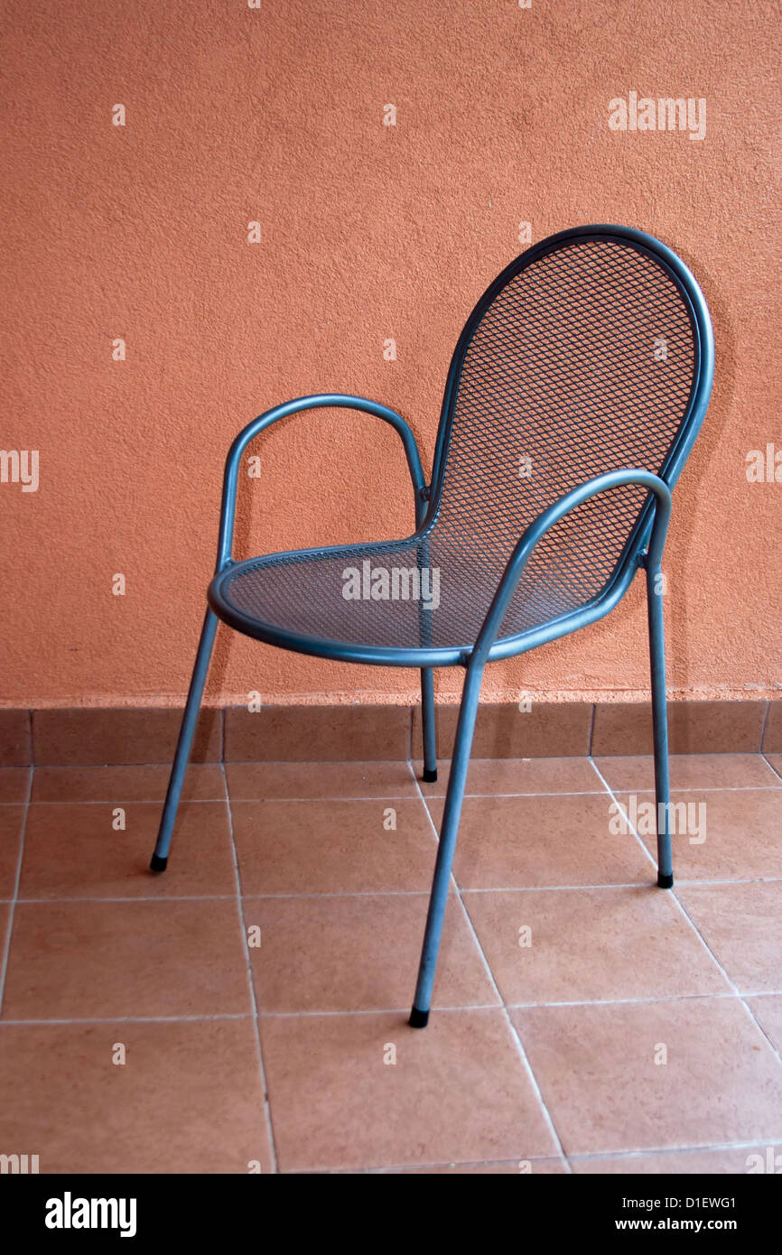 Empty metal chair against red wall background Stock Photo