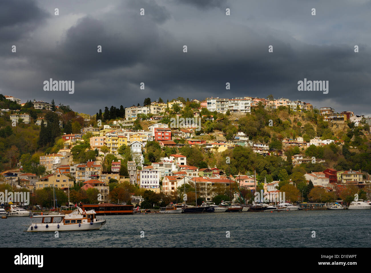 Sun on homes on a hillside of Arnavutkoy Besiktas Istanbul Turkey with storm clouds on the Bosphorus Strait Stock Photo