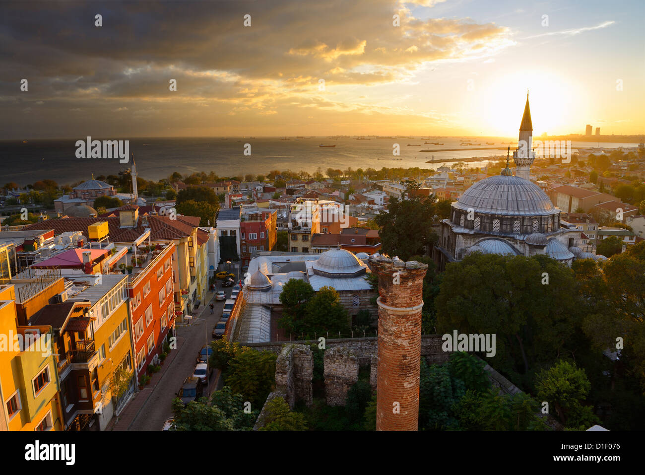 Setting sun behind the Sokollu Mehmet Pasha mosque minaret with golden glow on houses and Marmara Sea Istanbul Turkey Stock Photo