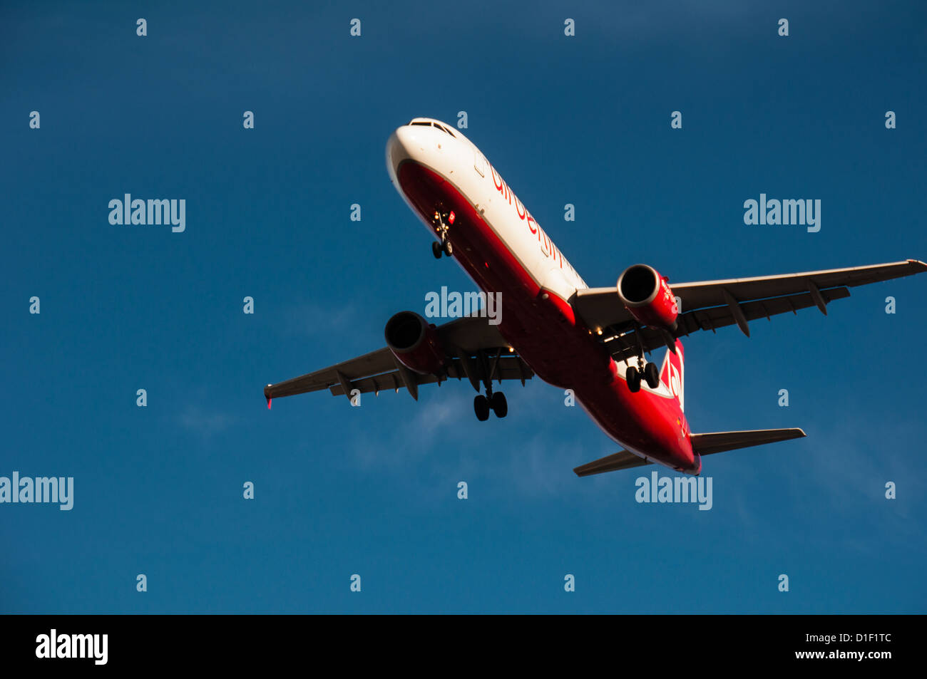 Red and white commercial plane approachs the landing strip Stock Photo