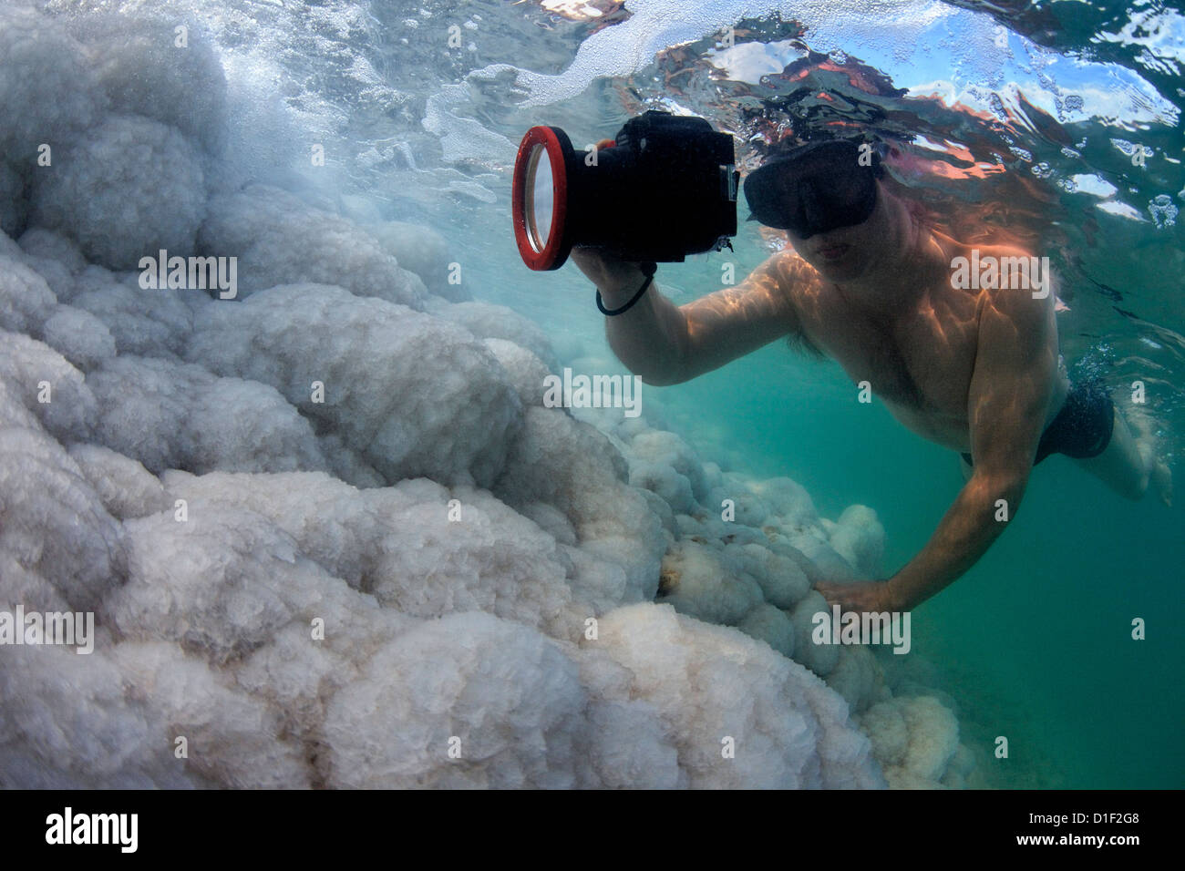 Man taking picture of salt crystal formations over rocks in the Dead Sea, Israel, underwater shot Stock Photo