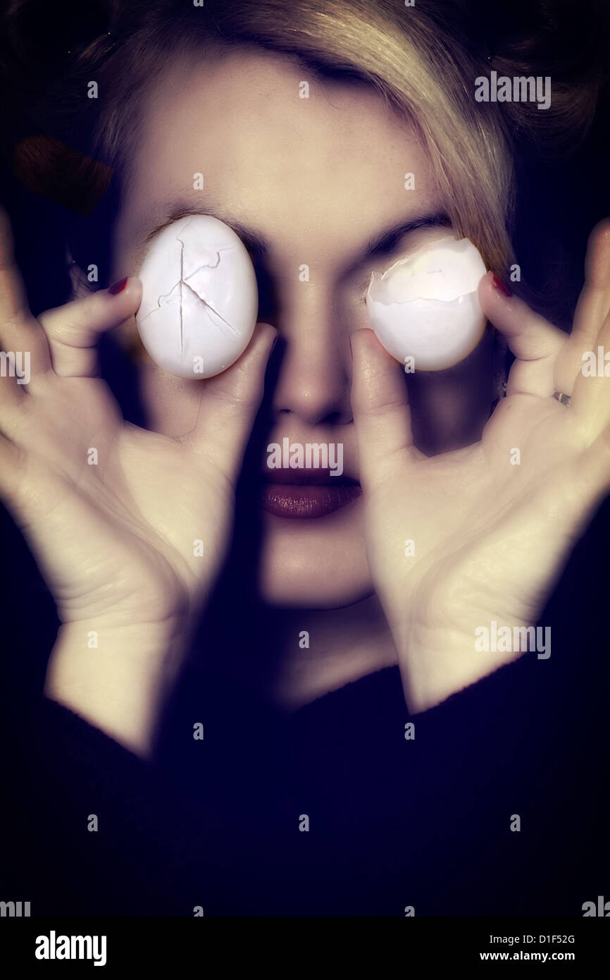 a woman is holding two broken eggs in front of her eyes Stock Photo