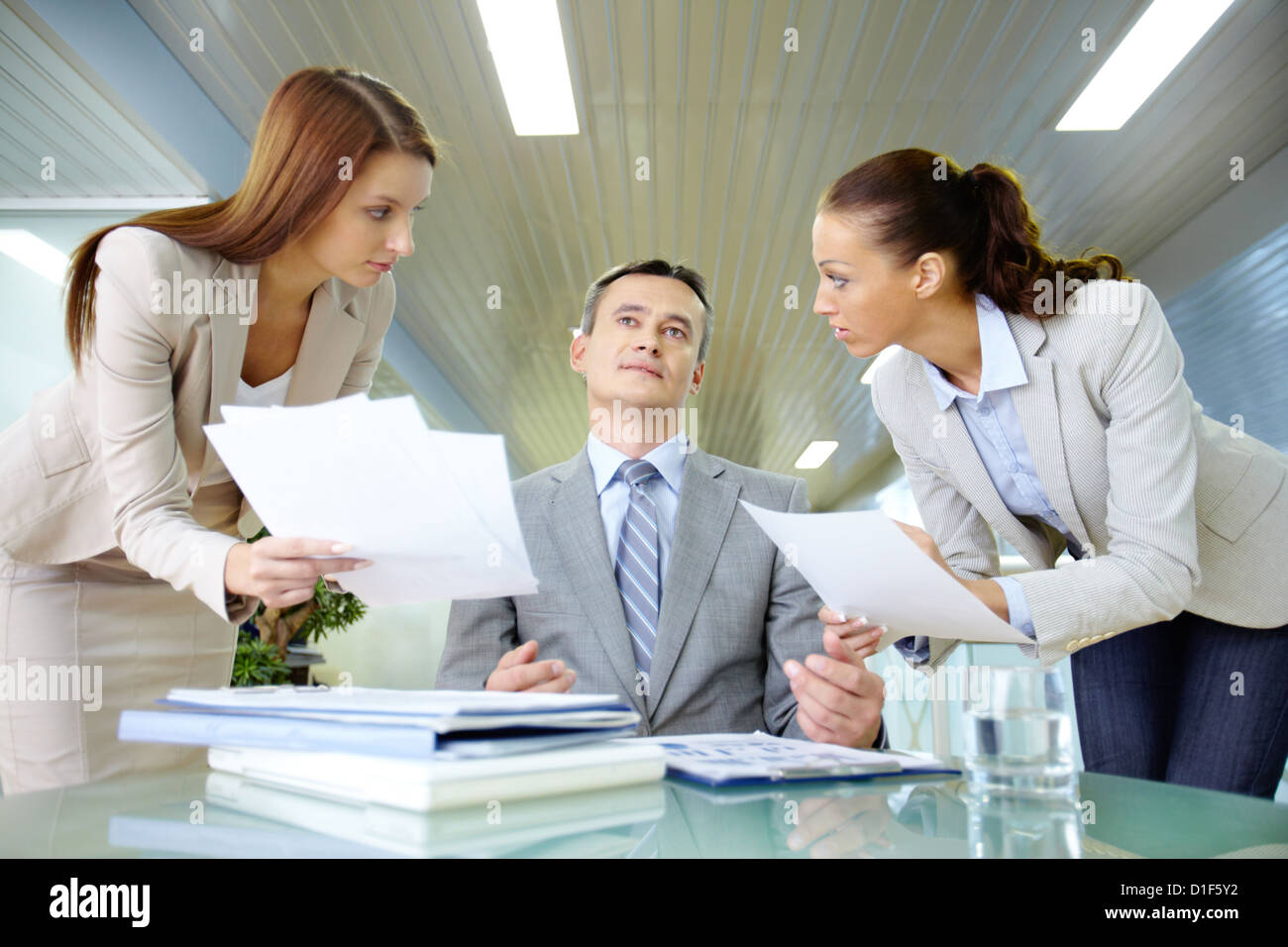 Inspirated boss sitting at workplace surrounded by two secretaries Stock Photo