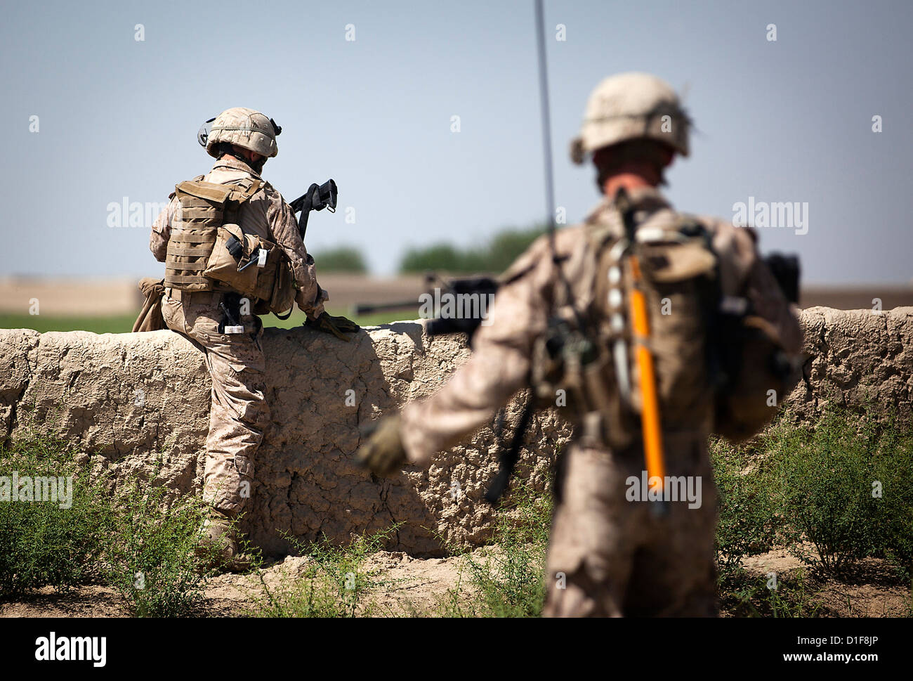 Two US Marines climb a wall separating two fields during a security patrol April 30, 2012 in Durzay, Afghanistan. Stock Photo