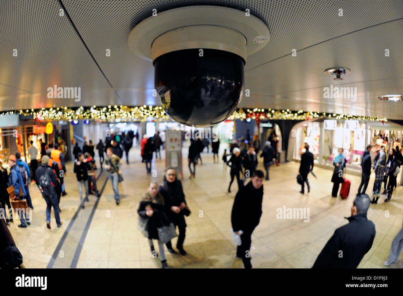 People walk under a surveillance camer at central station in Cologne