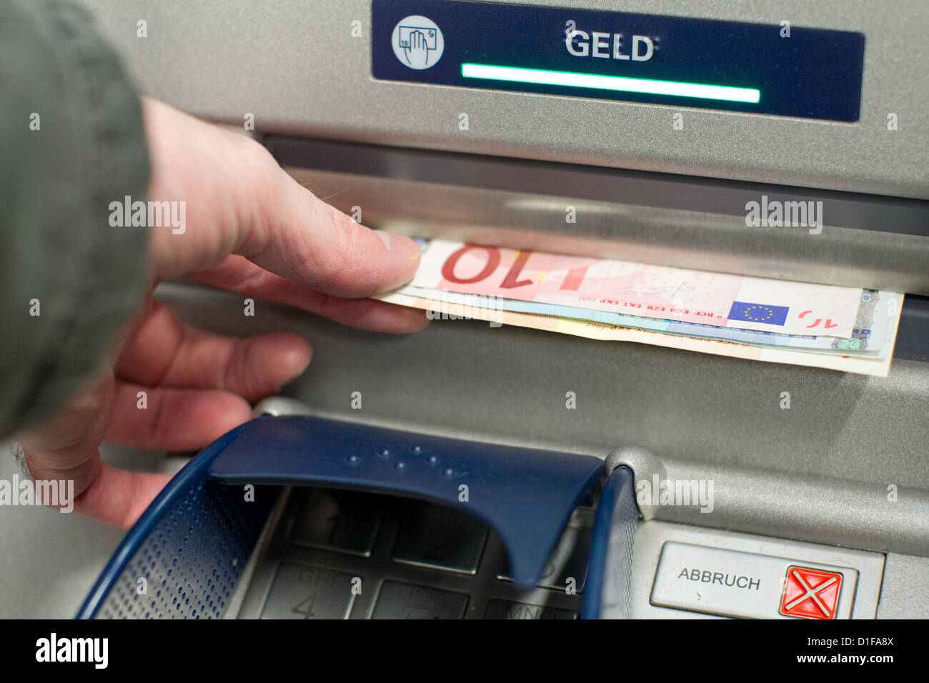 A man pulls euro banknotes from a cash dispenser in Osnabrueck, Germany, 13 December 2012. Christmas shooping is in full swing ten days ahead of the forthcoming Christmas festivities. Photo: Friso Gentsch Stock Photo