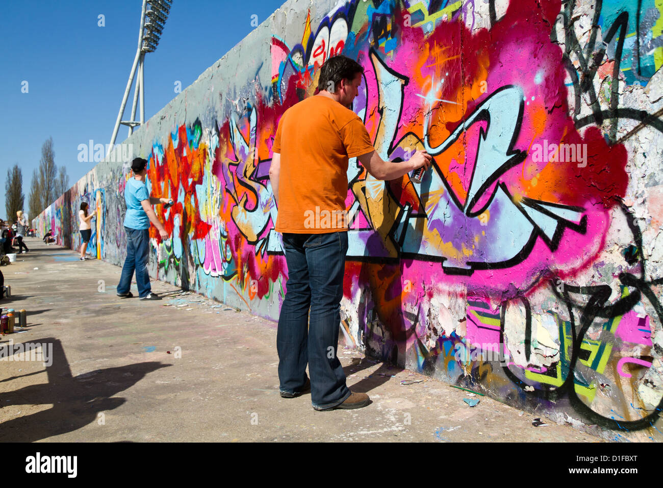 Young Sprayers painting Graffiti on the Remains of the Berlin Wall in