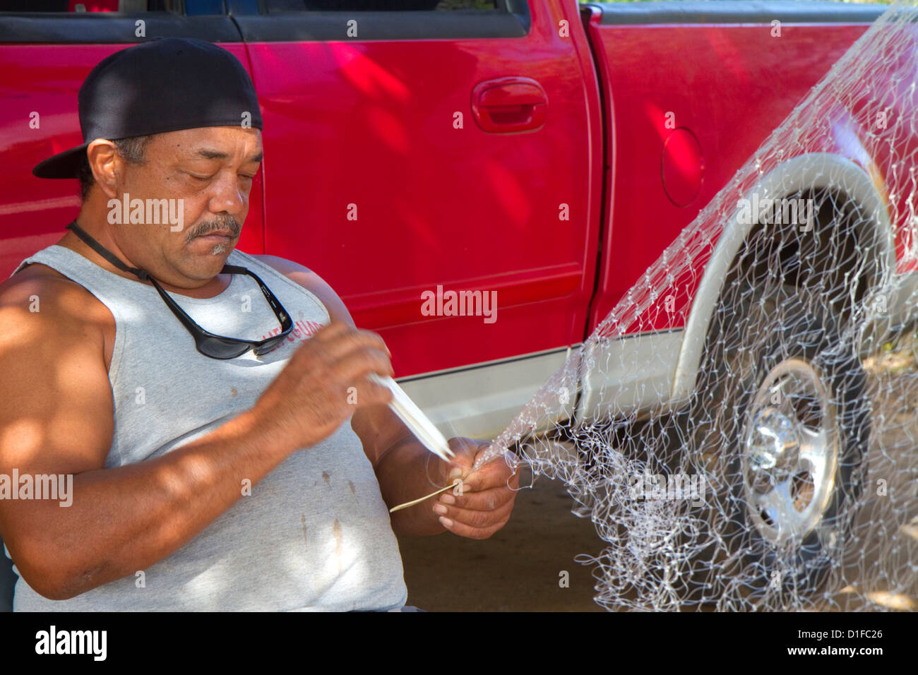 Native hawaiian fisherman mending a net on the island of Kauai, Hawaii