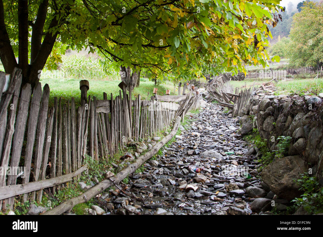 Footpath through fields in the southern Caucasus, stone fence and wooden fence Stock Photo