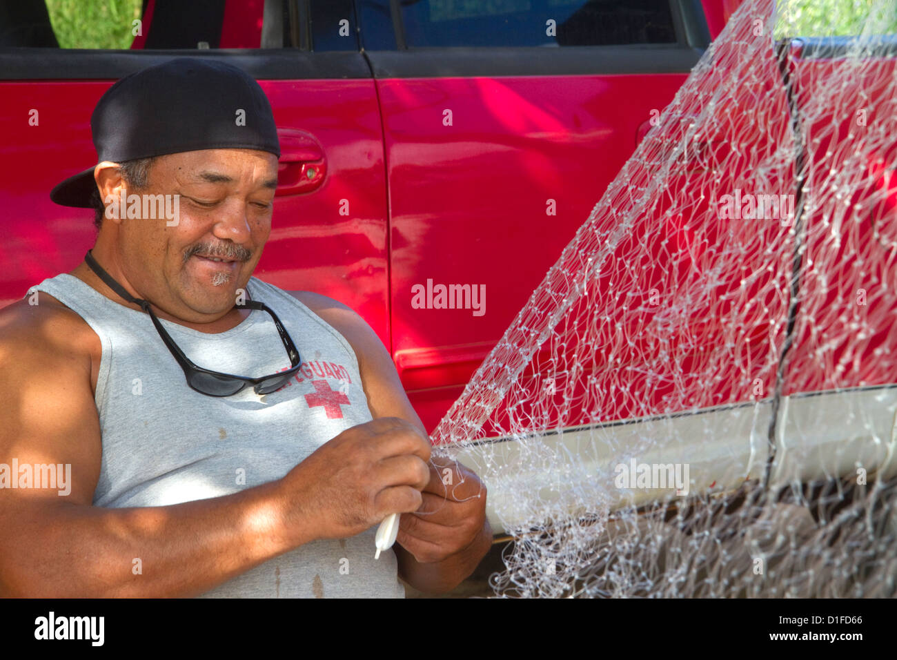 Native hawaiian fisherman mending a net on the island of Kauai, Hawaii, USA. MR Stock Photo