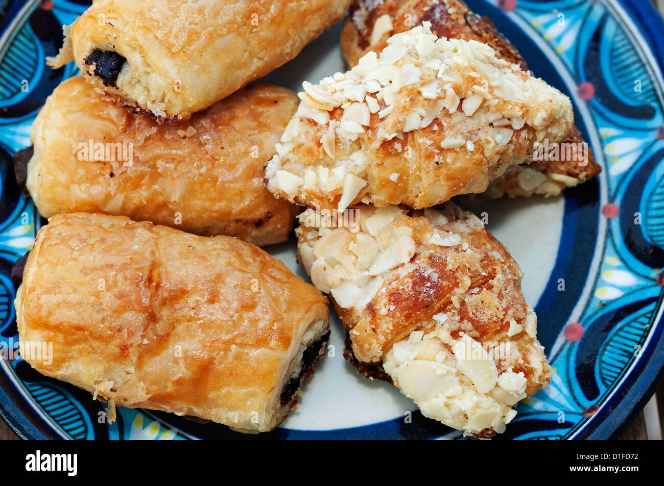 A plate is filled with an assortment of miniature chocolate and almond croissants. Stock Photo