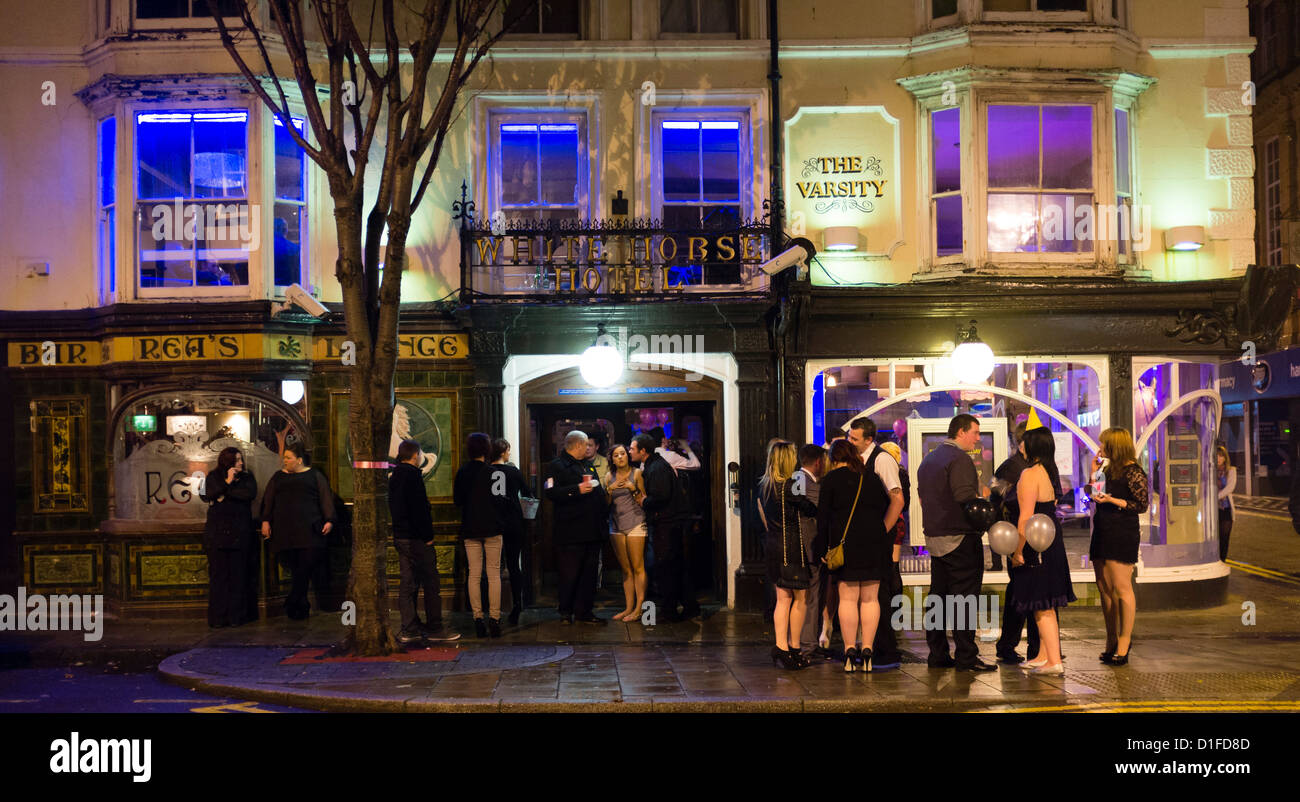 Exterior, at night groups of young people standing talking and smoking outside The Varsity pub bar, Aberystwyth Wales UK Stock Photo