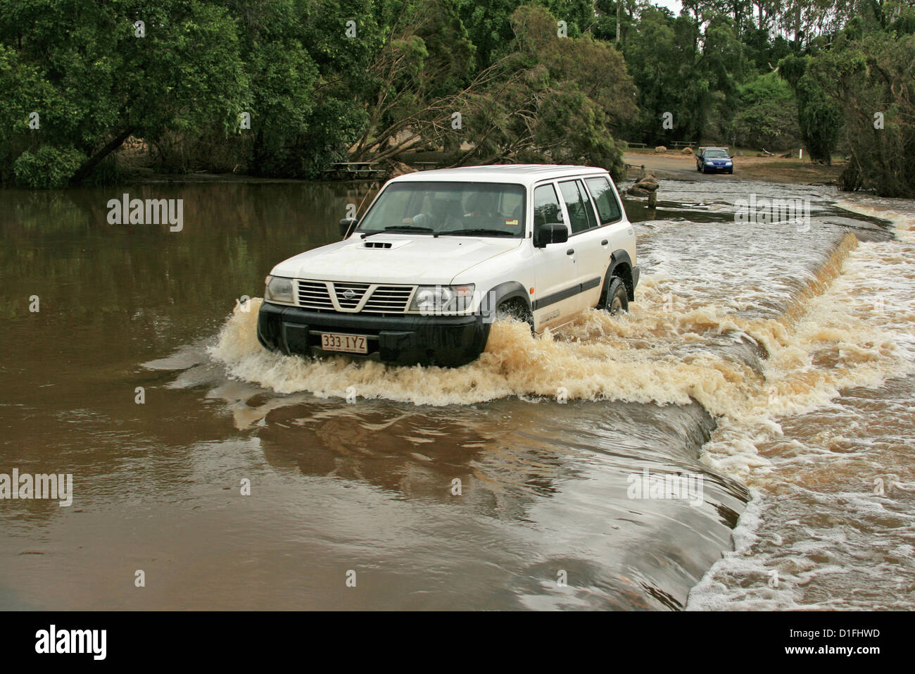 White four wheel drive vehicle on road crossing through deep water of