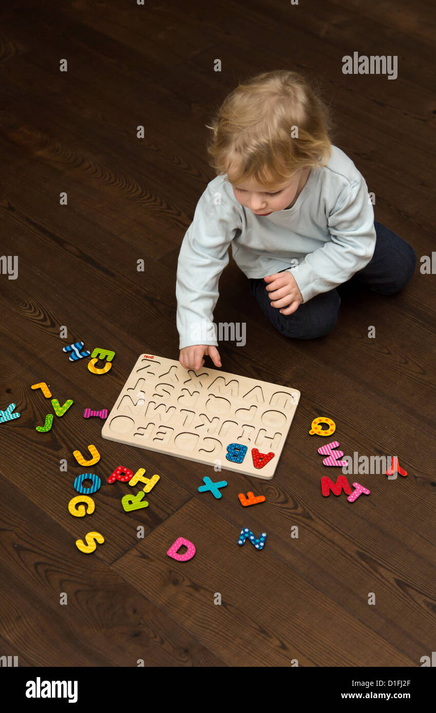 Jeune garçon, 2 ans, joue avec un puzzle ABC, alphabet Photo Stock