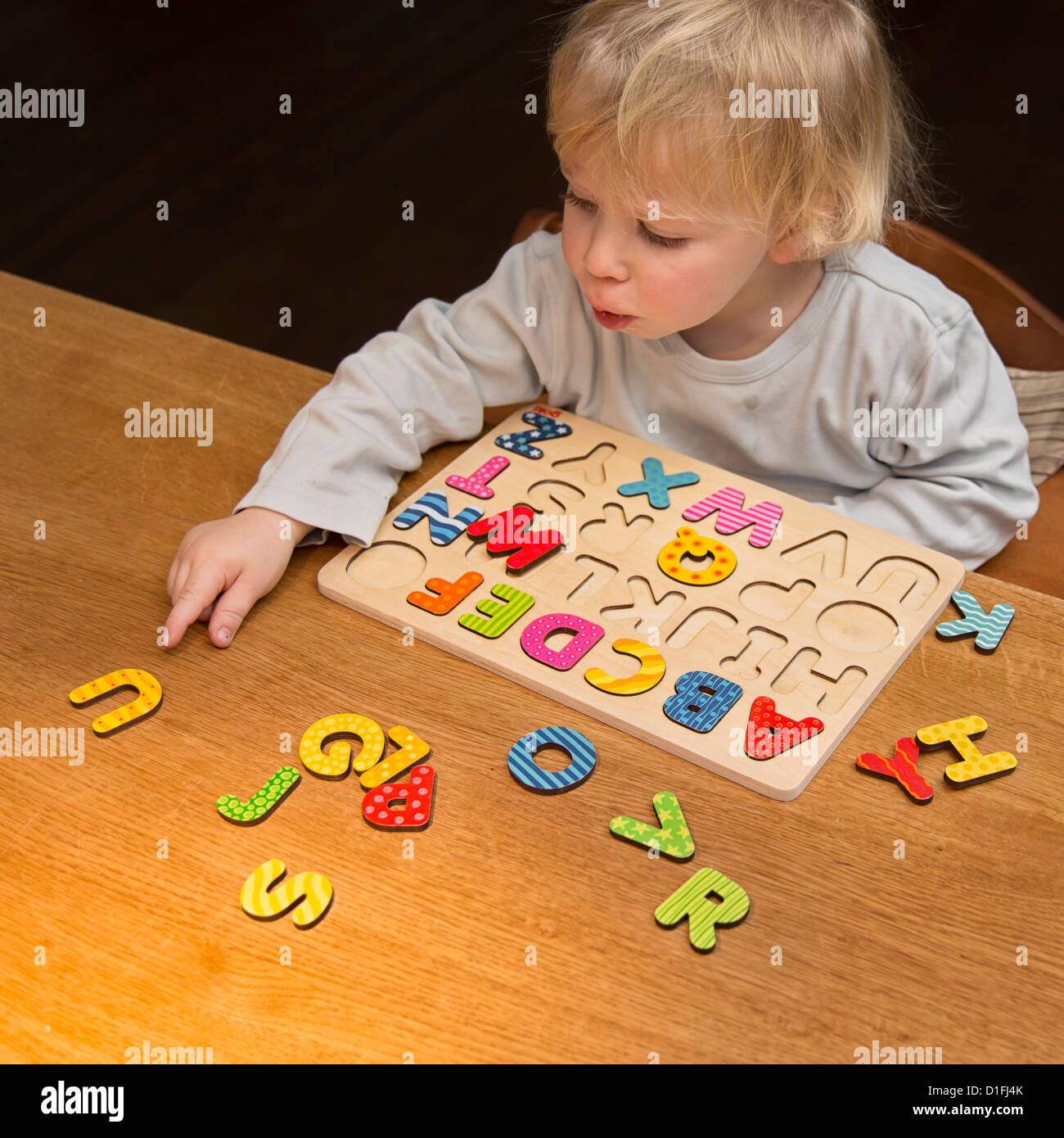 Young boy, 2 years old, playing with an ABC puzzle, alphabet Stock Photo