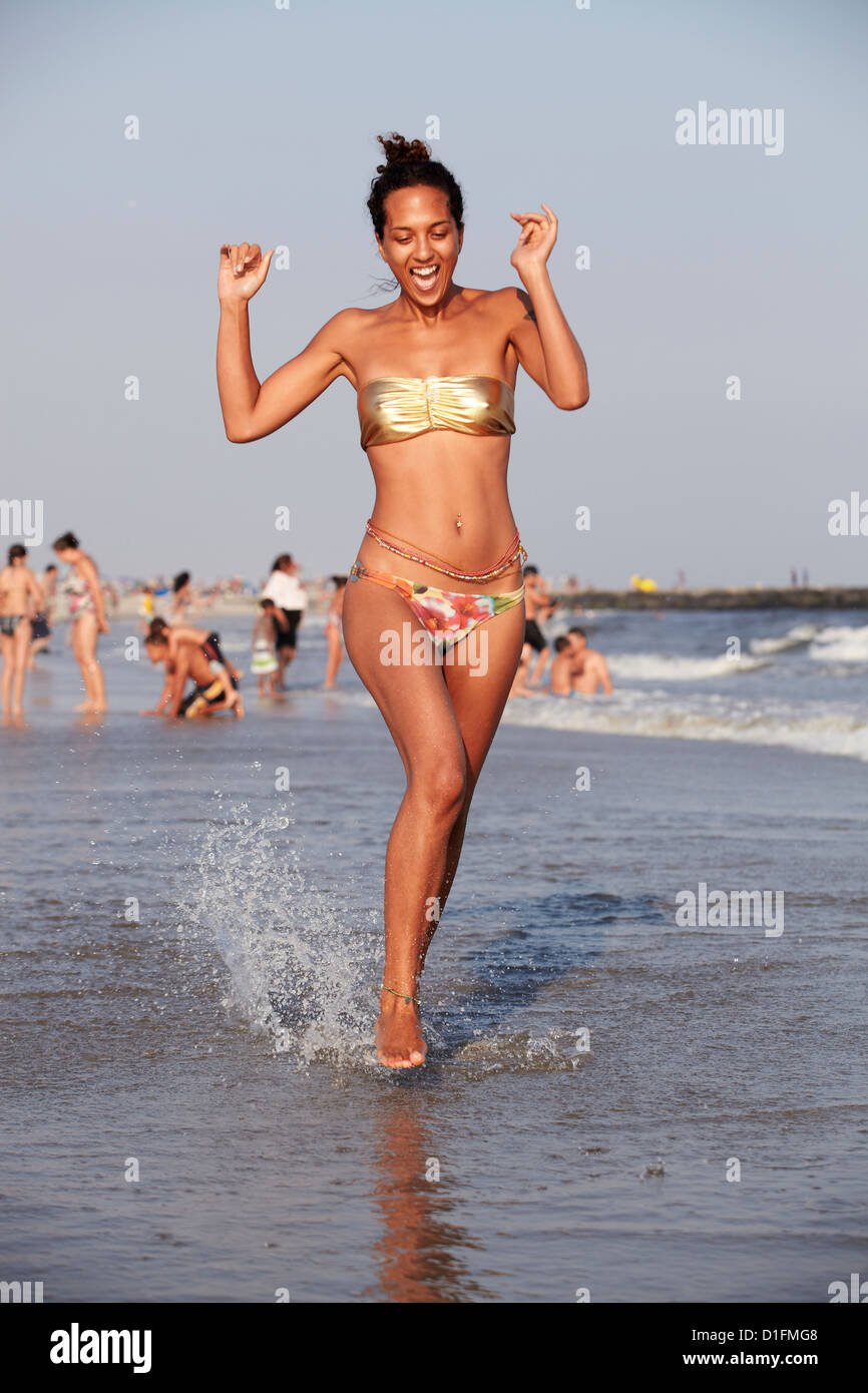 Mixed race woman wading in ocean on beach Stock Photo