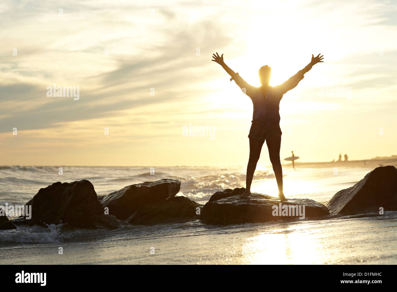 Black woman with arms raised on beach Stock Photo