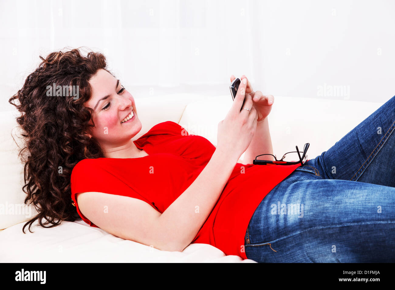 Girl with mobile phone lying on the sofa Stock Photo - Alamy